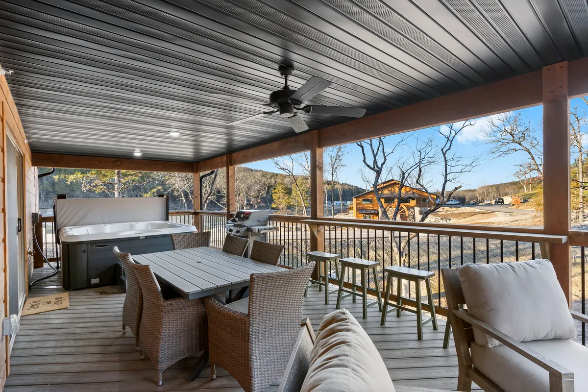 This image captures a private outdoor deck featuring a hot tub, a dining table, outdoor seating, a grill, and an expansive view of the surrounding landscape. The setting is tranquil and designed for both relaxation and social gatherings, highlighting the seamless indoor-outdoor flow described in the section.