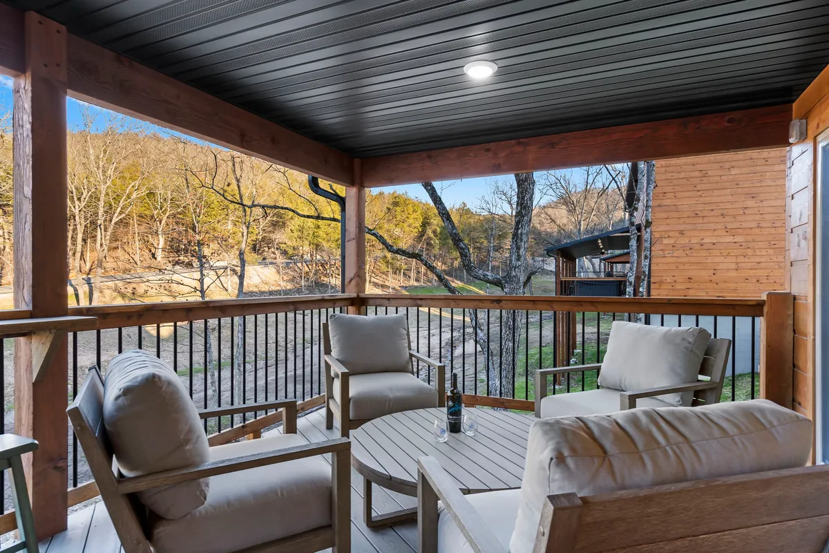 The hero image showcases the cabin's inviting exterior, featuring comfortable seating on a spacious wooden deck surrounded by natural beauty. The vantage point offers sweeping landscape views, perfect for enjoying breathtaking sunsets or stargazing on clear nights. The tranquil setting beckons guests to relax with a morning coffee, gather with loved ones, or unwind with a good book.