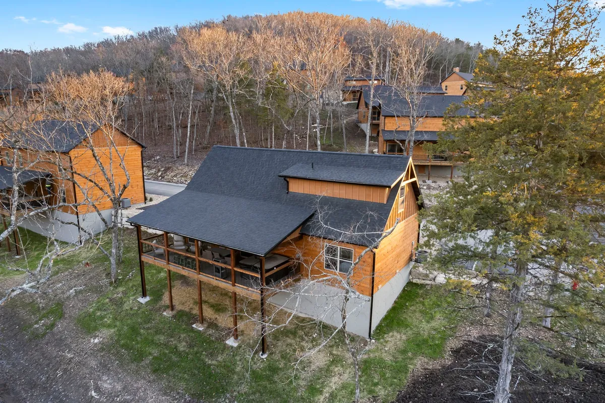A tranquil exterior shot of a wooden cabin nestled among trees beneath a clear sky. The porch offers inviting views ideal for morning coffee or relaxing after a walk. The surrounding landscape suggests immediate access to walking trails and outdoor adventures.